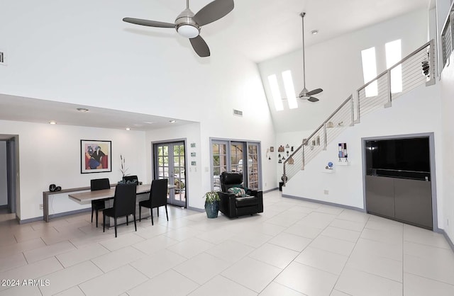 tiled living room featuring ceiling fan, a towering ceiling, and french doors