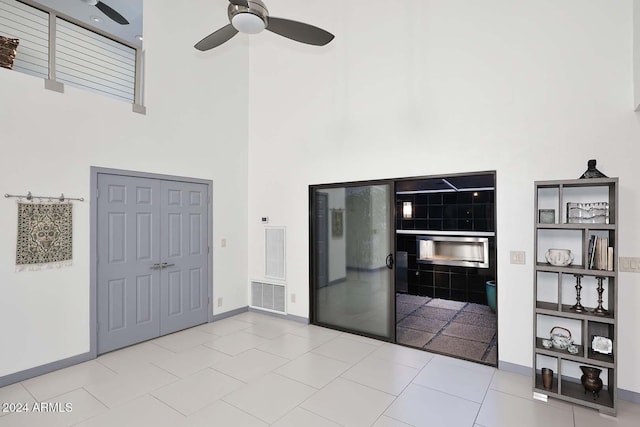 interior space with ceiling fan, a fireplace, and a high ceiling