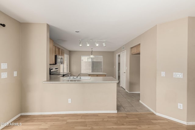 kitchen with stainless steel appliances, light wood finished floors, a peninsula, and light countertops