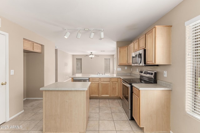 kitchen with a ceiling fan, a peninsula, light tile patterned flooring, light brown cabinetry, and stainless steel appliances