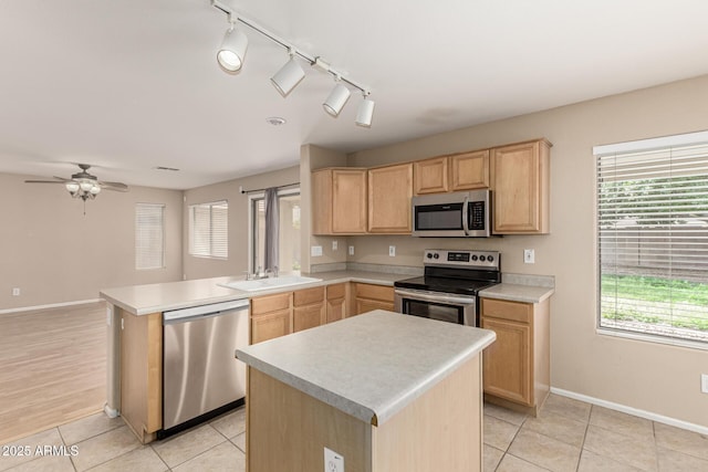 kitchen featuring light brown cabinets, a sink, appliances with stainless steel finishes, a peninsula, and light countertops