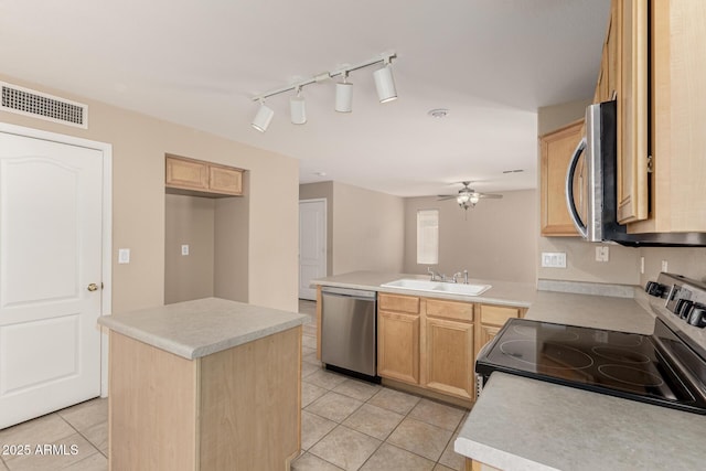 kitchen featuring visible vents, a peninsula, stainless steel appliances, a ceiling fan, and a sink