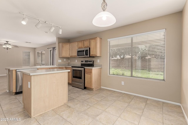 kitchen featuring a peninsula, light brown cabinetry, stainless steel appliances, light countertops, and a center island