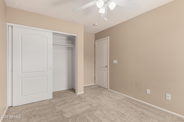 unfurnished bedroom with light carpet, baseboards, a closet, and a ceiling fan