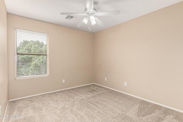 carpeted empty room with visible vents, baseboards, and ceiling fan