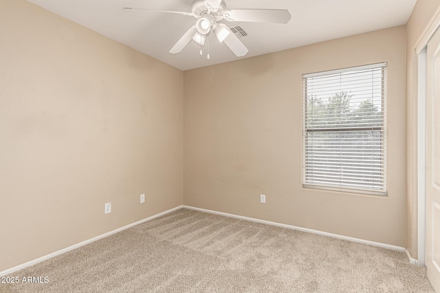 carpeted empty room with a ceiling fan, visible vents, and baseboards