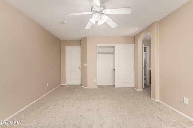 unfurnished bedroom featuring visible vents, baseboards, arched walkways, a closet, and carpet flooring