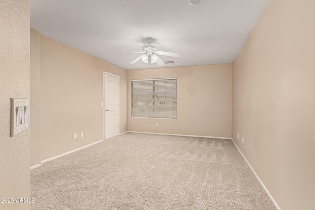 carpeted empty room with visible vents, baseboards, and a ceiling fan