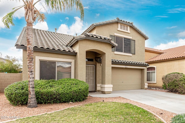 mediterranean / spanish house with a tiled roof, an attached garage, driveway, and stucco siding