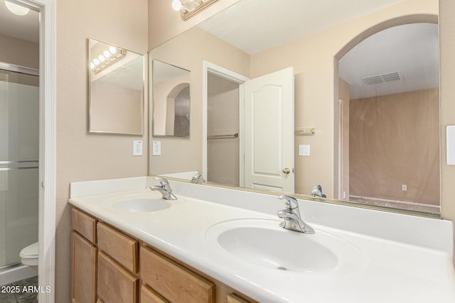 bathroom featuring double vanity, visible vents, a stall shower, and a sink