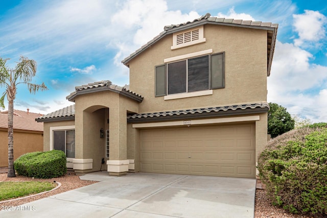 mediterranean / spanish home with a tile roof, a garage, driveway, and stucco siding