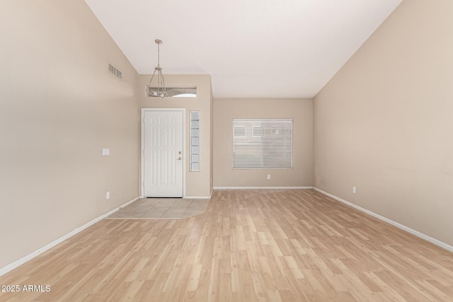 interior space with lofted ceiling, baseboards, visible vents, and light wood-type flooring