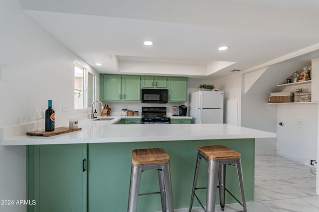 kitchen featuring black appliances, a breakfast bar area, kitchen peninsula, and green cabinetry