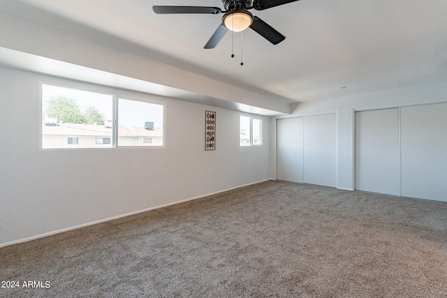 unfurnished bedroom with two closets, ceiling fan, and carpet