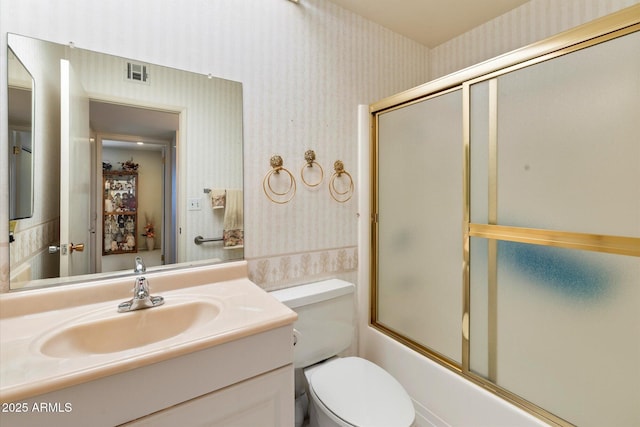 full bathroom with bath / shower combo with glass door, visible vents, vanity, and wallpapered walls