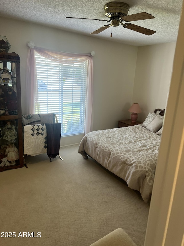 carpeted bedroom with a ceiling fan and a textured ceiling