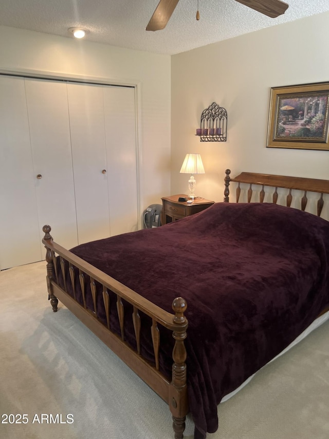 carpeted bedroom featuring a textured ceiling, a closet, and a ceiling fan