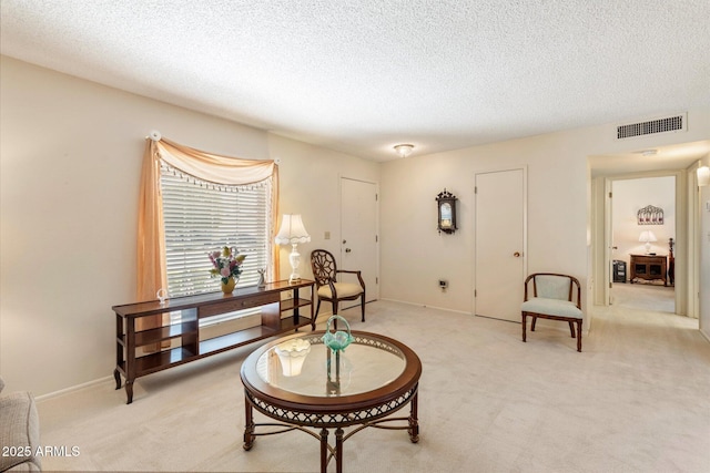 sitting room with a textured ceiling, carpet, and visible vents