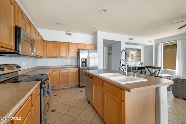 kitchen featuring light tile patterned floors, an island with sink, ceiling fan, sink, and appliances with stainless steel finishes