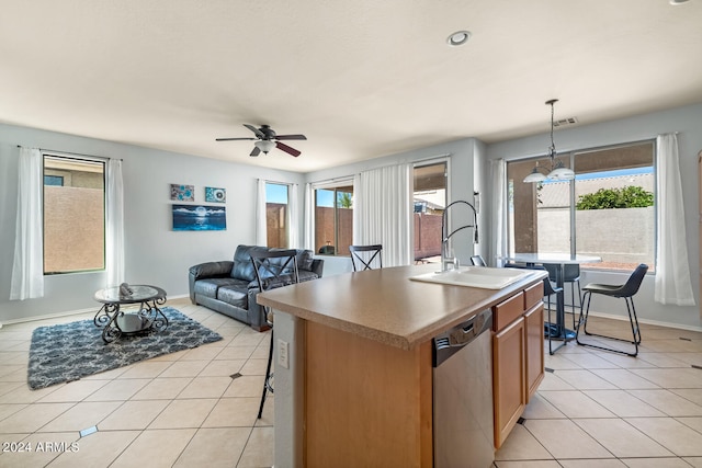 kitchen featuring hanging light fixtures, dishwasher, sink, ceiling fan, and a kitchen island with sink