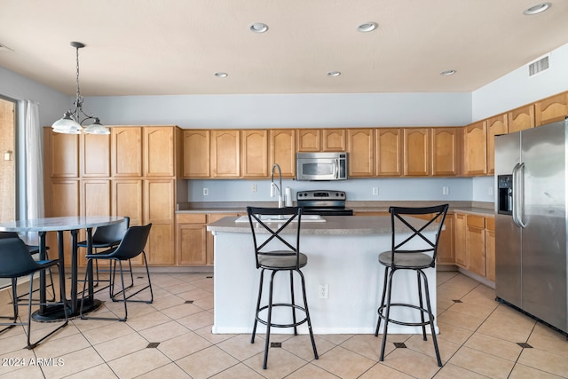 kitchen with hanging light fixtures, a kitchen breakfast bar, appliances with stainless steel finishes, and a kitchen island with sink