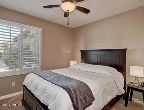 carpeted bedroom with ceiling fan and baseboards