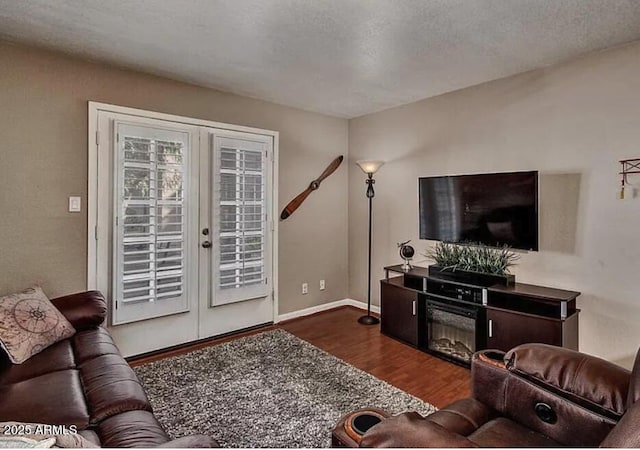 living room featuring french doors, a textured ceiling, dark wood-type flooring, and baseboards