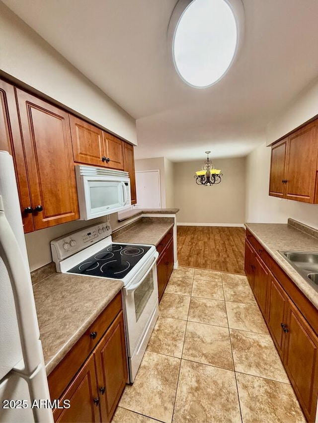kitchen with brown cabinetry, a notable chandelier, and white appliances