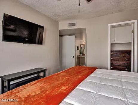 bedroom with a ceiling fan, visible vents, and a textured ceiling
