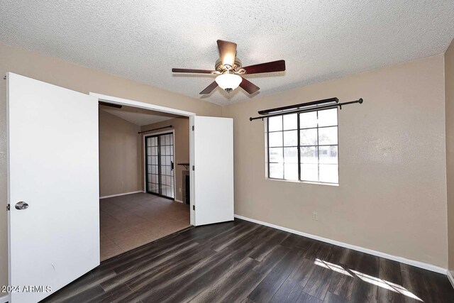 unfurnished bedroom with ceiling fan, dark wood-type flooring, a textured ceiling, and a closet