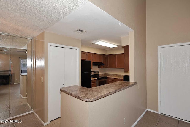 kitchen with black refrigerator, light tile patterned floors, stainless steel electric range, and kitchen peninsula