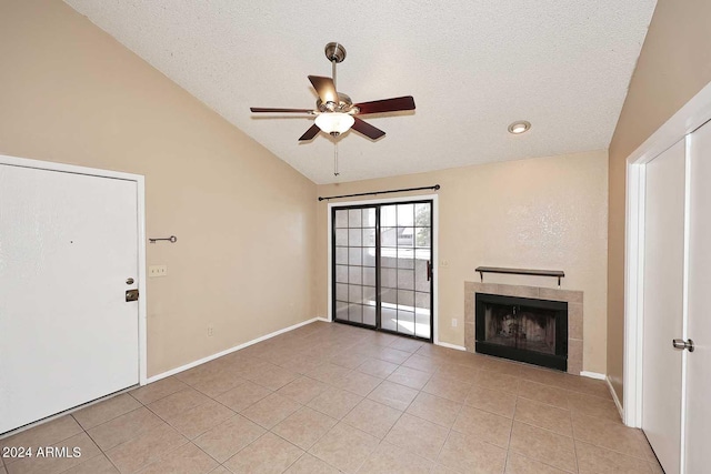 unfurnished living room featuring lofted ceiling, a tiled fireplace, light tile patterned floors, ceiling fan, and a textured ceiling