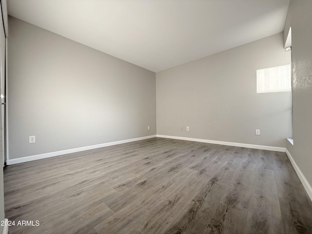 empty room with light wood-type flooring and vaulted ceiling