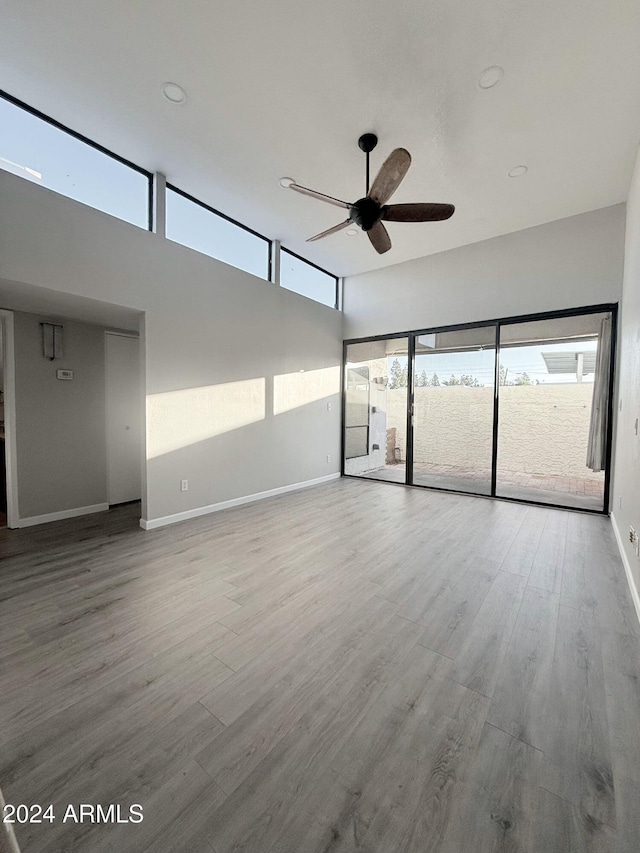 spare room featuring a high ceiling, hardwood / wood-style flooring, and ceiling fan