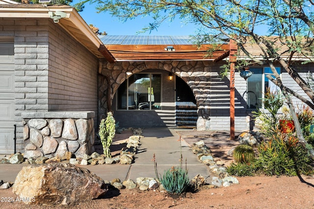 entrance to property featuring solar panels and a patio