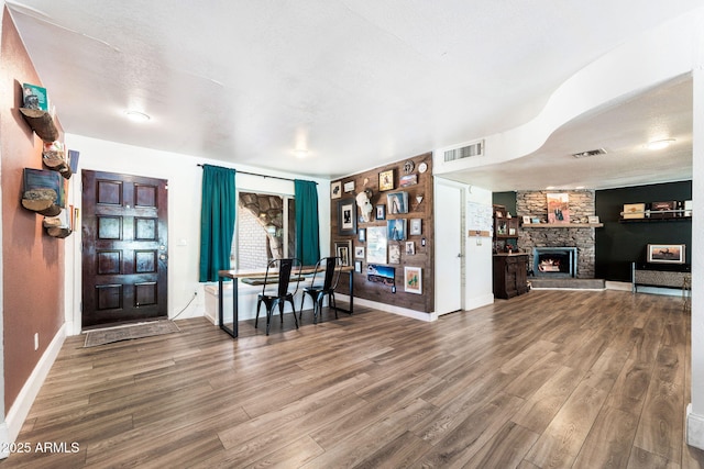 interior space with hardwood / wood-style floors, a textured ceiling, and a stone fireplace