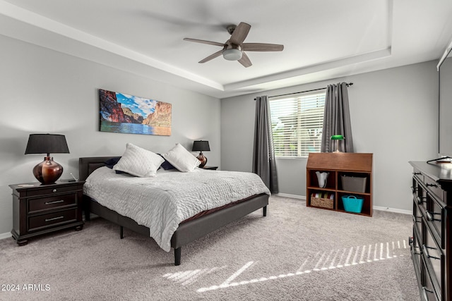 carpeted bedroom with ceiling fan and a tray ceiling