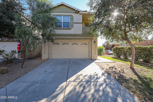 traditional-style house featuring a balcony, an attached garage, concrete driveway, and stucco siding