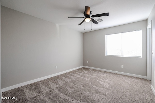 carpeted spare room featuring a ceiling fan, visible vents, and baseboards