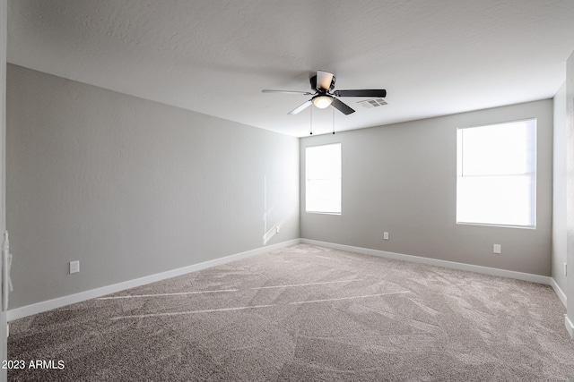 carpeted empty room featuring visible vents, ceiling fan, a textured ceiling, and baseboards