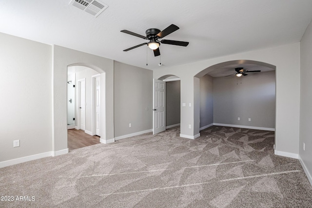 spare room featuring carpet floors, visible vents, and arched walkways