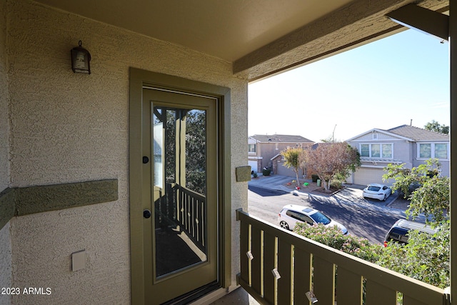 doorway to property with a balcony, a residential view, and stucco siding