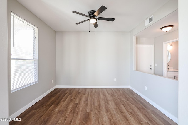 empty room featuring ceiling fan, wood finished floors, visible vents, and baseboards