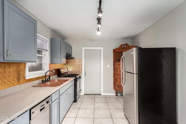 kitchen featuring stainless steel appliances, tasteful backsplash, light countertops, light tile patterned flooring, and a sink