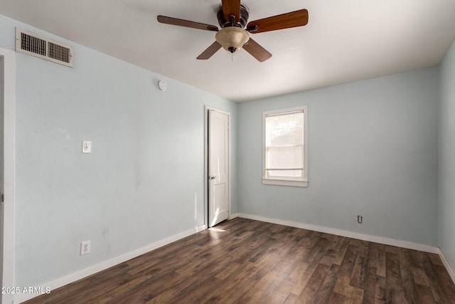 empty room featuring a ceiling fan, visible vents, dark wood finished floors, and baseboards