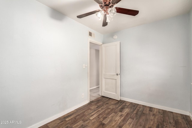 empty room featuring ceiling fan, dark wood-type flooring, visible vents, and baseboards