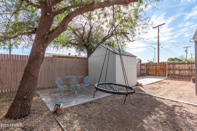 view of yard featuring a patio area, a fenced backyard, a storage unit, and an outbuilding