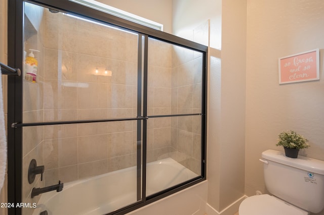 bathroom with toilet and bath / shower combo with glass door