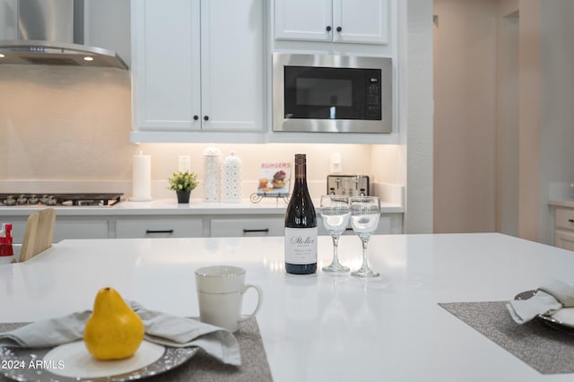 kitchen featuring white cabinets, appliances with stainless steel finishes, and wall chimney exhaust hood