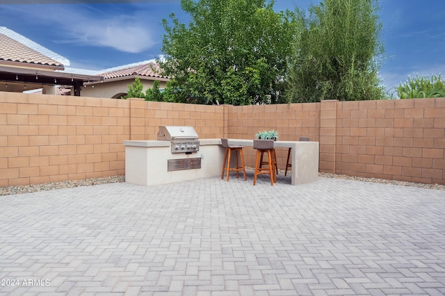 view of patio featuring a grill, a bar, and exterior kitchen